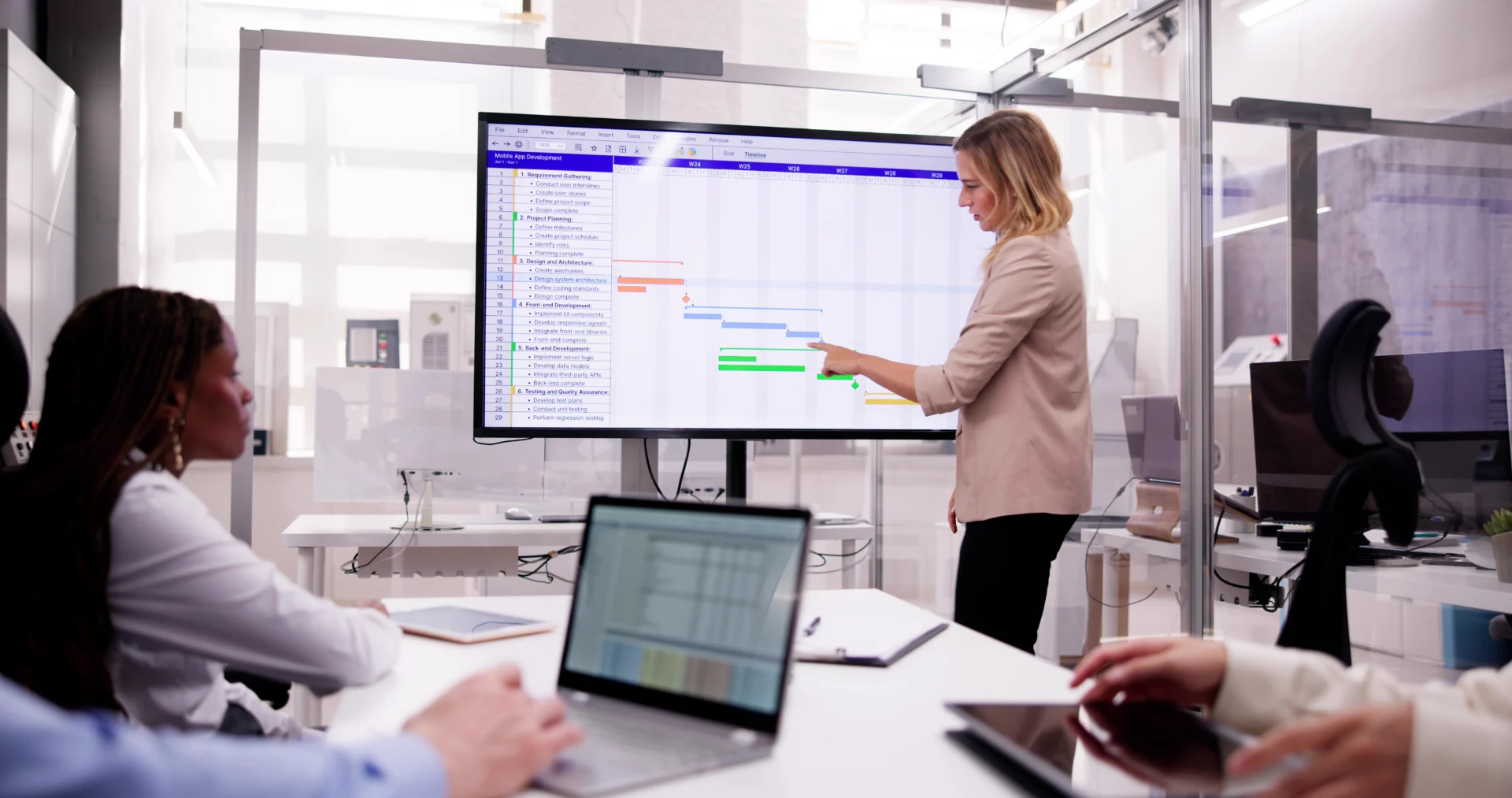 Frau präsentiert Gantt-Diagramm auf grossem Bildschirm während einer Besprechung bei 4D Bauprojekte GmbH – effektive Projektsteuerung.