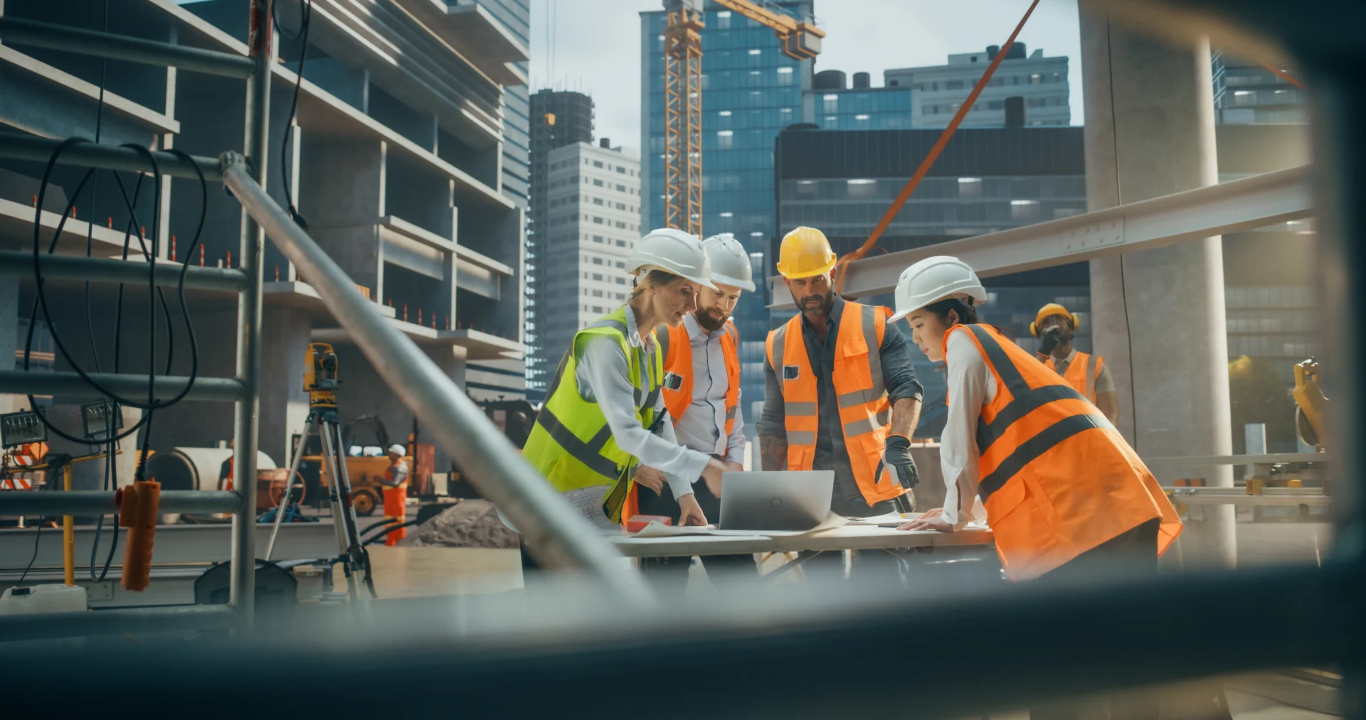 Bauleitungsteam mit Schutzwesten und Helmen bespricht Baupläne an einem Tisch auf der Baustelle – 4D Bauprojekte GmbH.